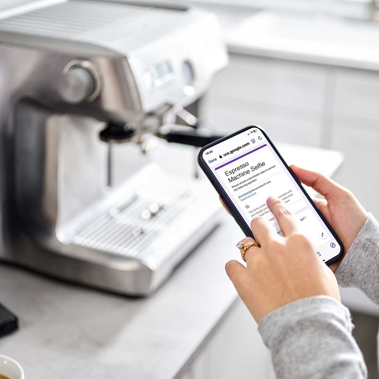 A person is holding a cell phone in front of a coffee machine reading the directions