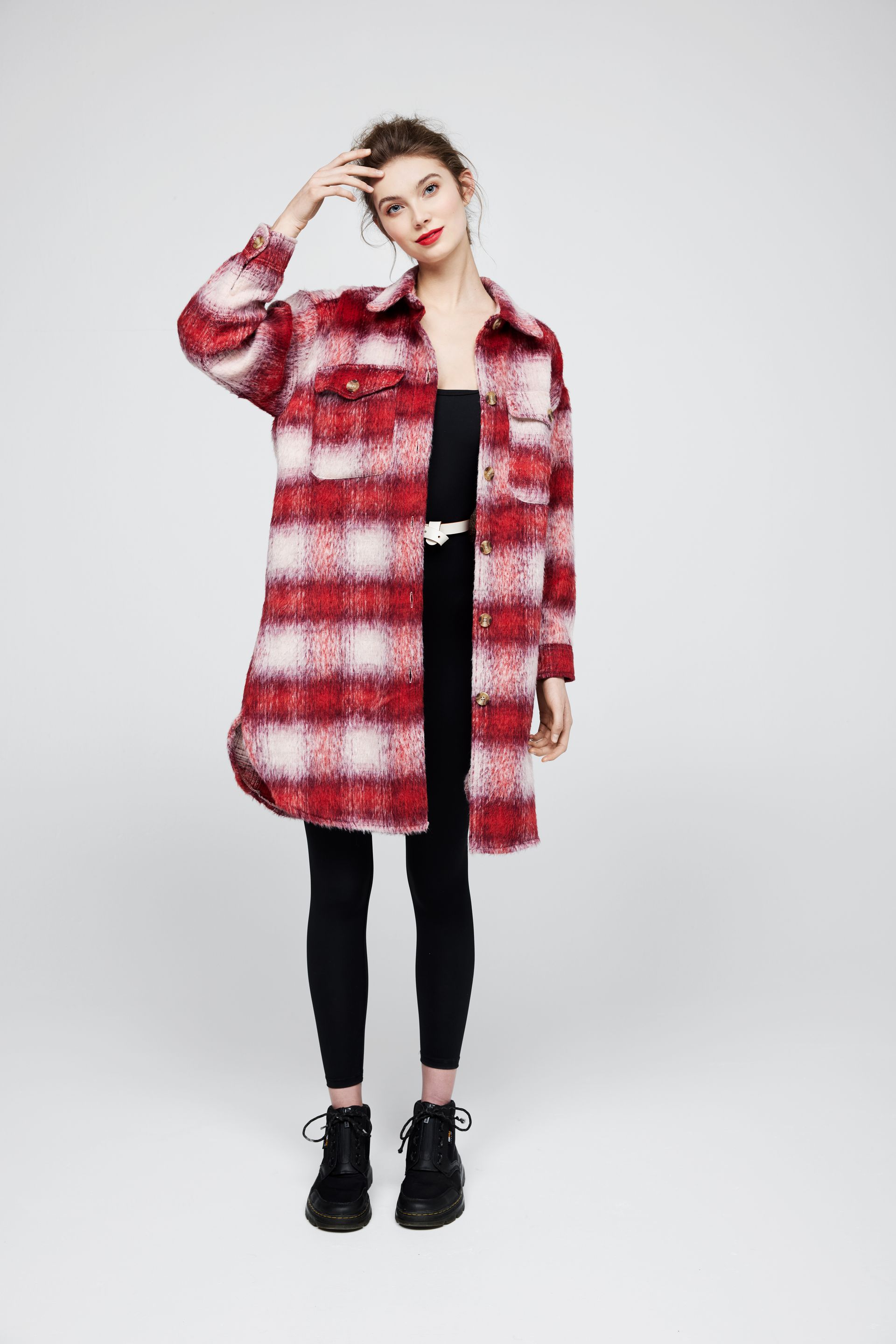 A woman is wearing a red and white plaid jacket and black pants.