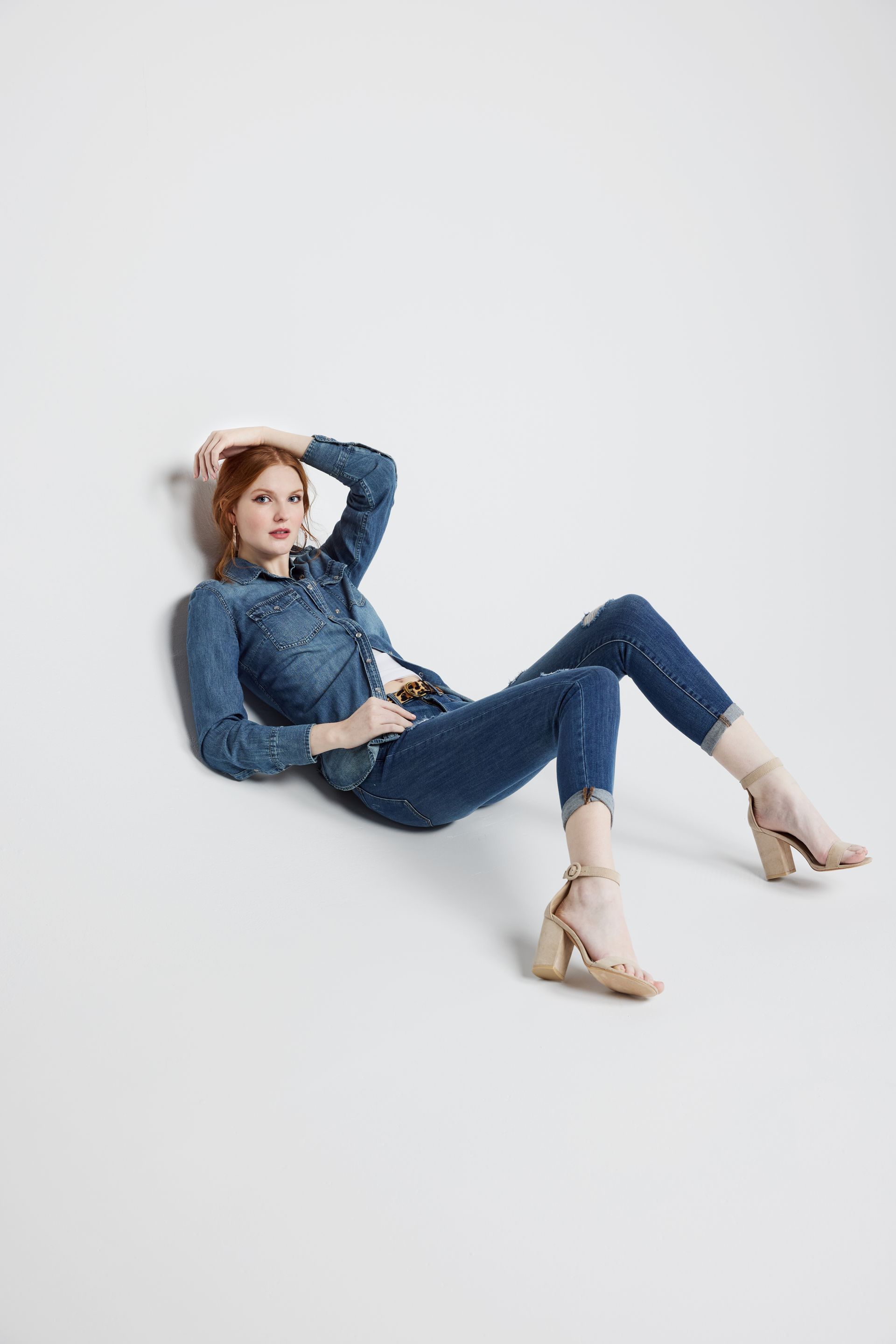 A woman in a denim shirt and jeans is laying on the floor.