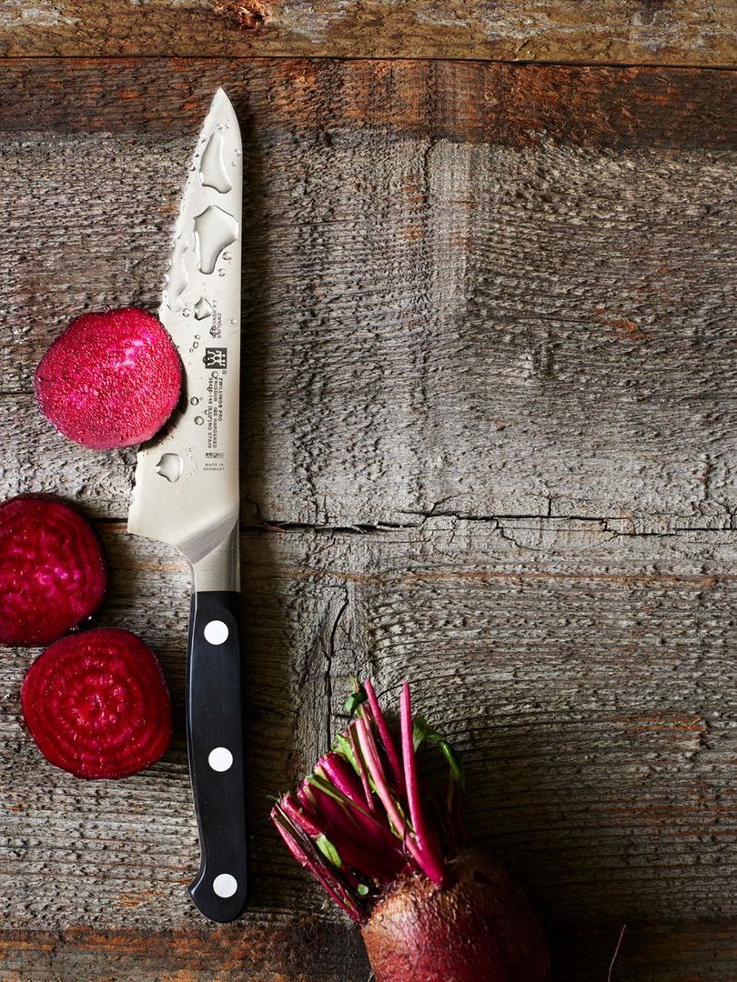A knife cutting a beet on wooden table