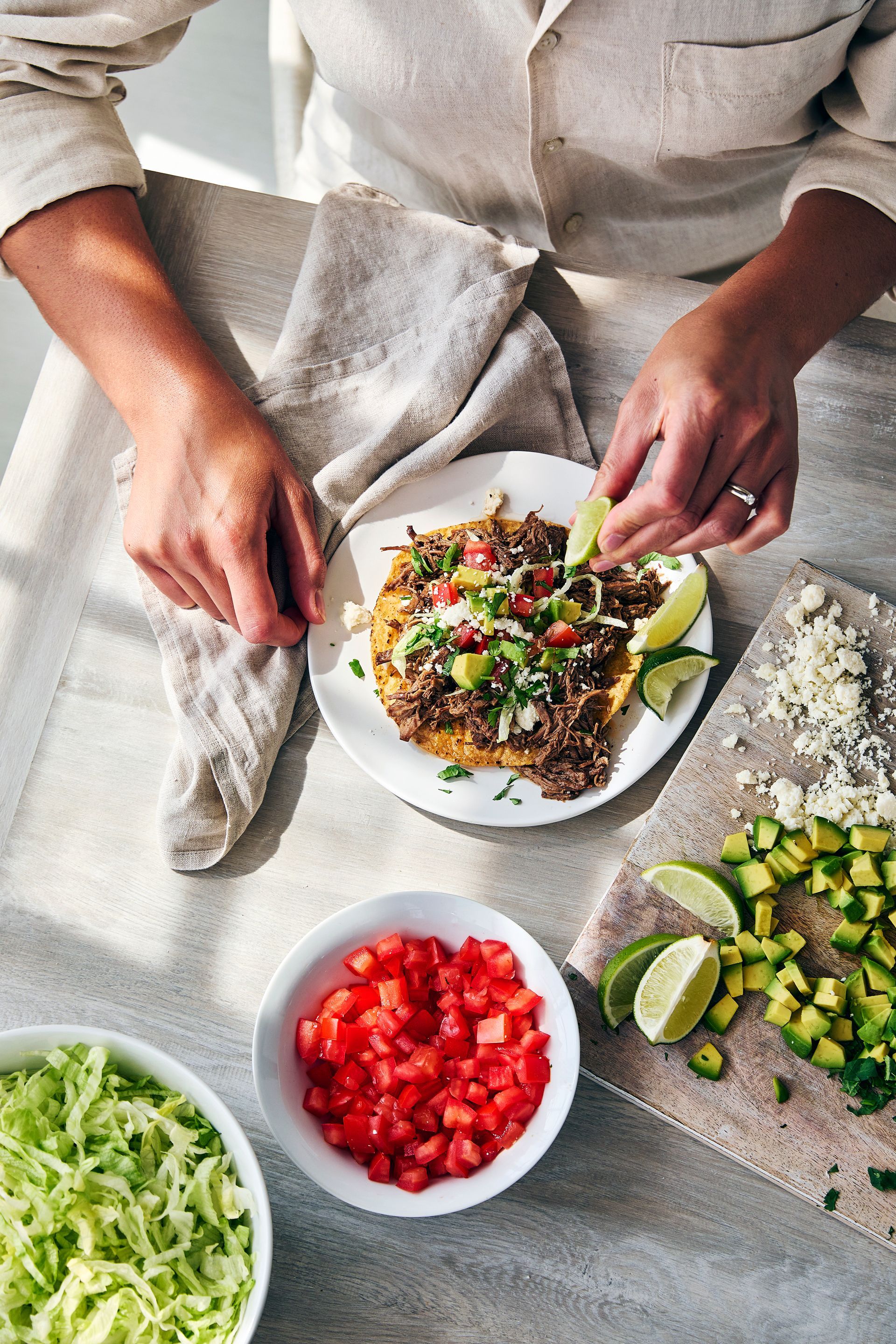 A person is making a tortilla with meat and vegetables on a plate.