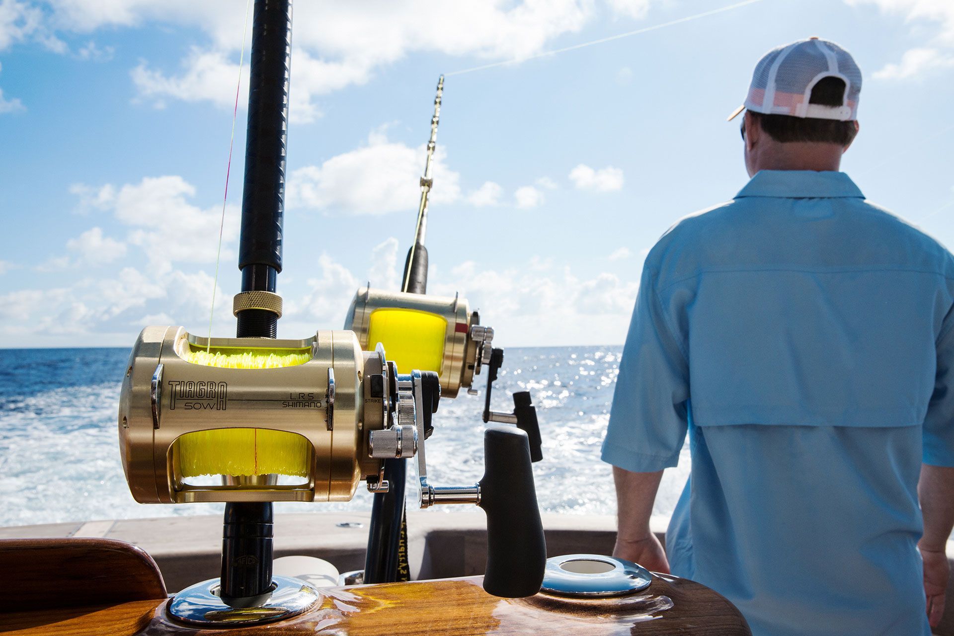 A man is standing on a Hatteras yacht looking at the ocean while fishing