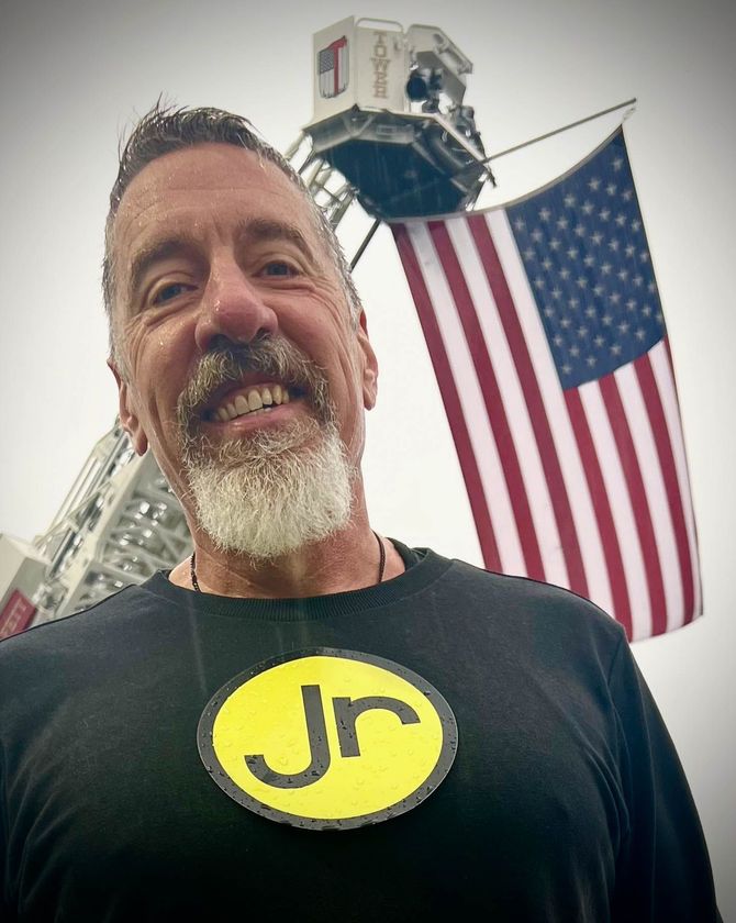 A man wearing a black shirt with the letter JR on it