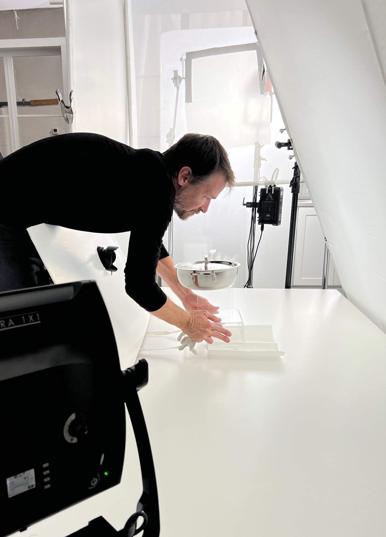 A photographer is kneeling down on a table in front of a camera.