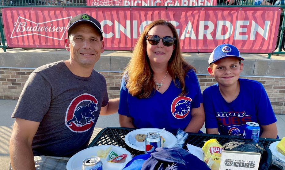 A family is sitting at a table in front of a sign that says chicago garden