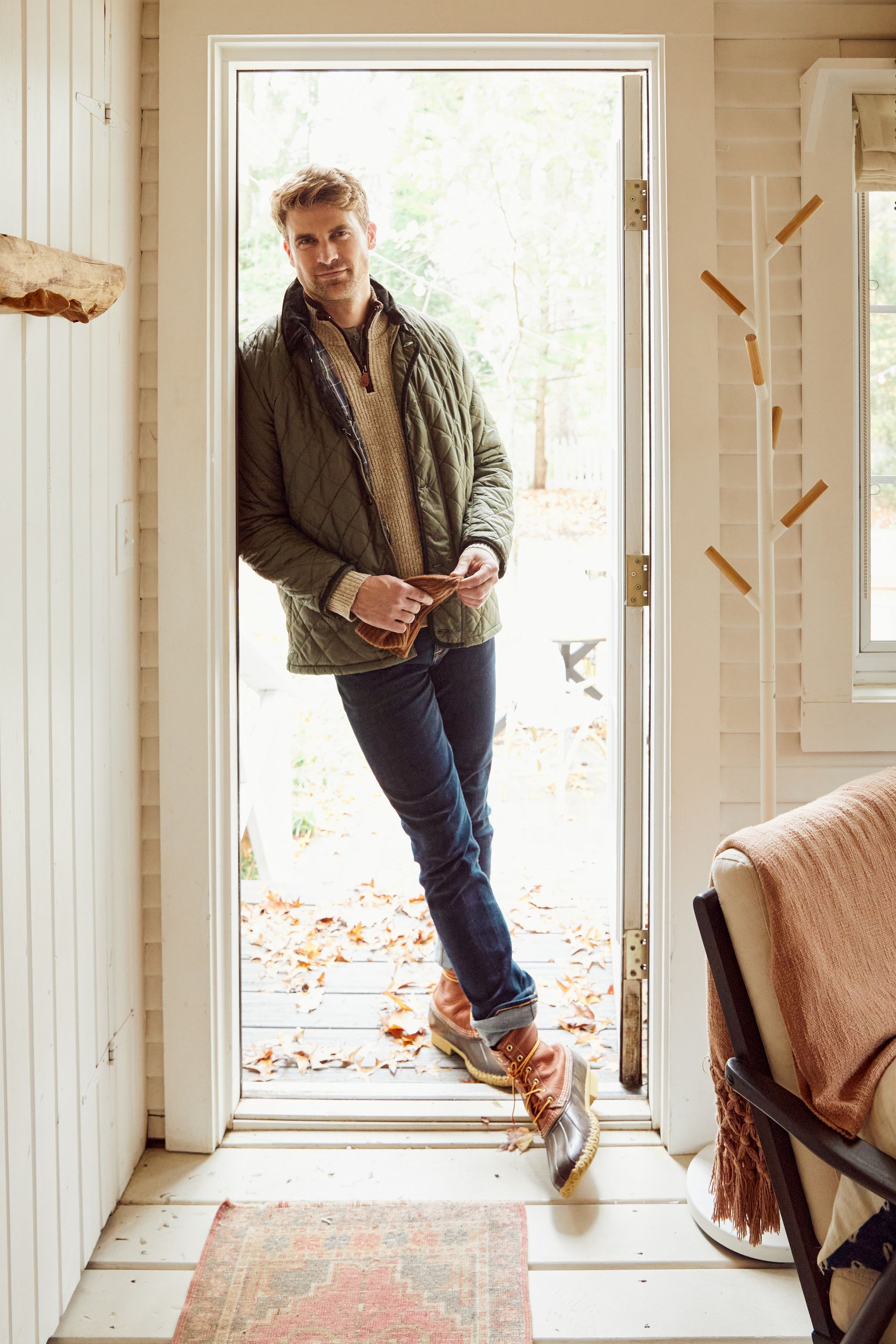 A man in a green jacket is standing in a doorway.
