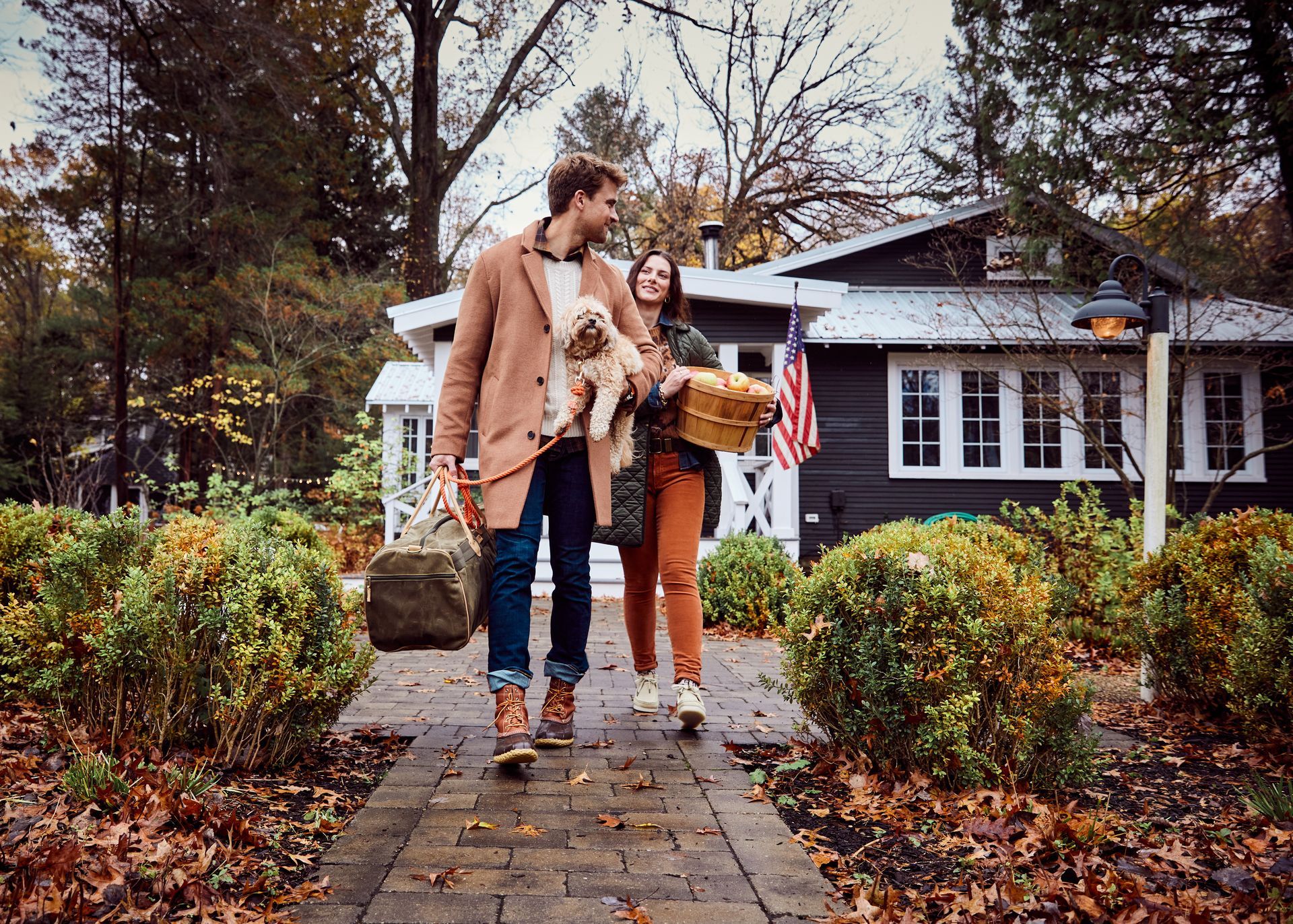 A man and woman are walking down a sidewalk with a dog.
