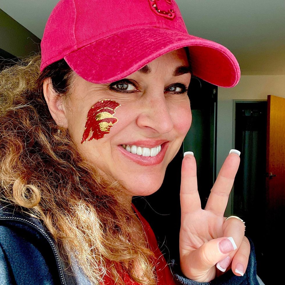 A woman wearing a pink hat giving a peace sign