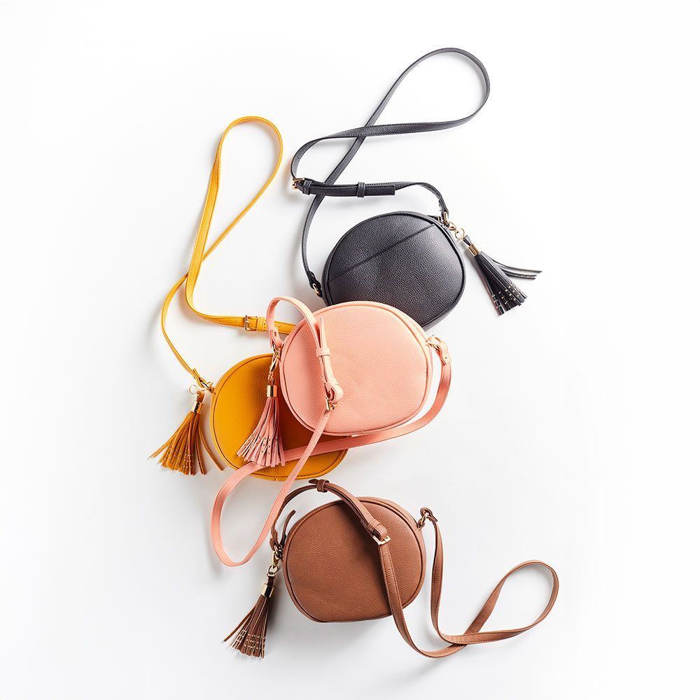 A group of round handbags with tassels are stacked on top of each other on a white surface.