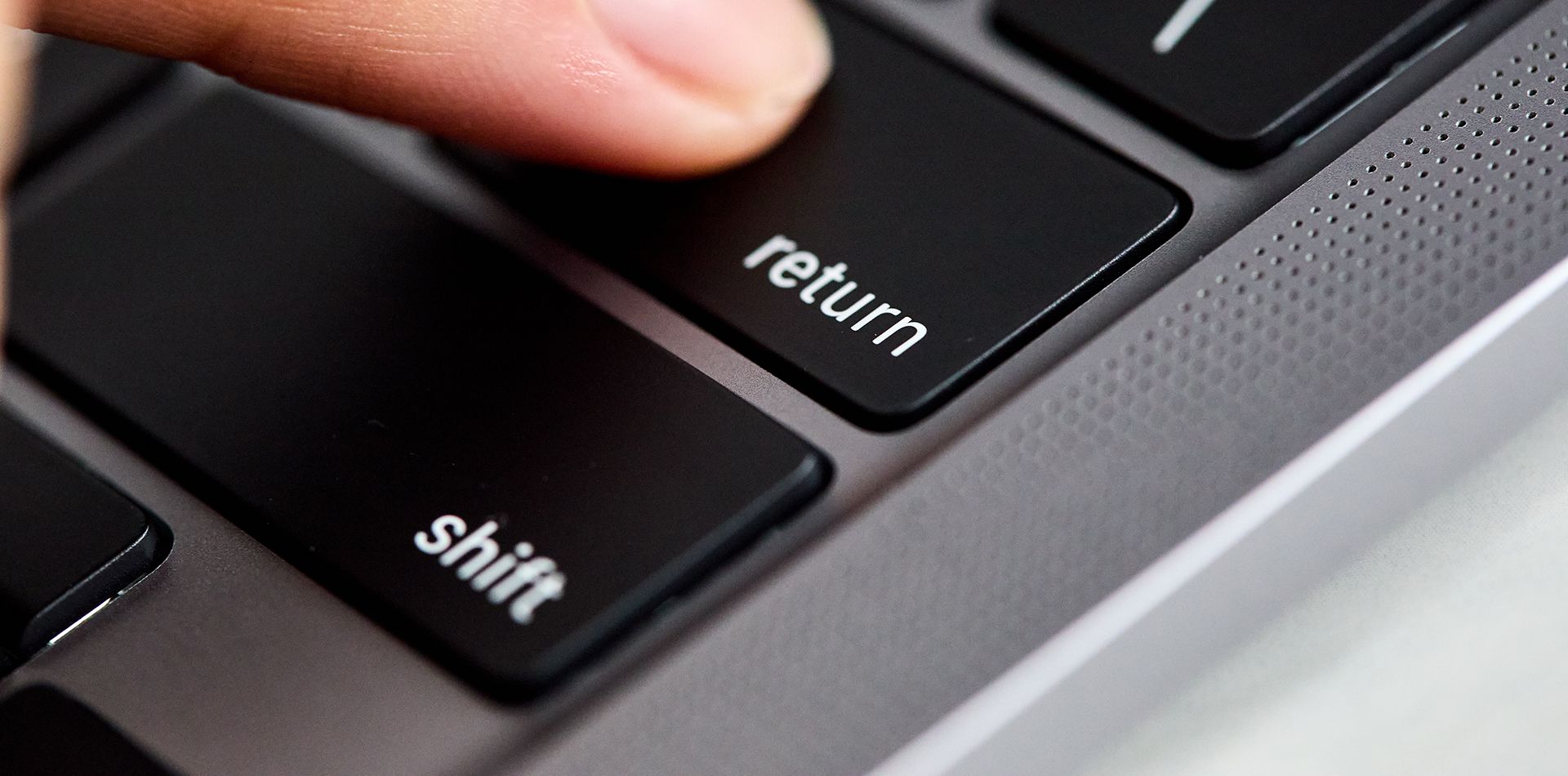 A person is pressing the return key on a keyboard