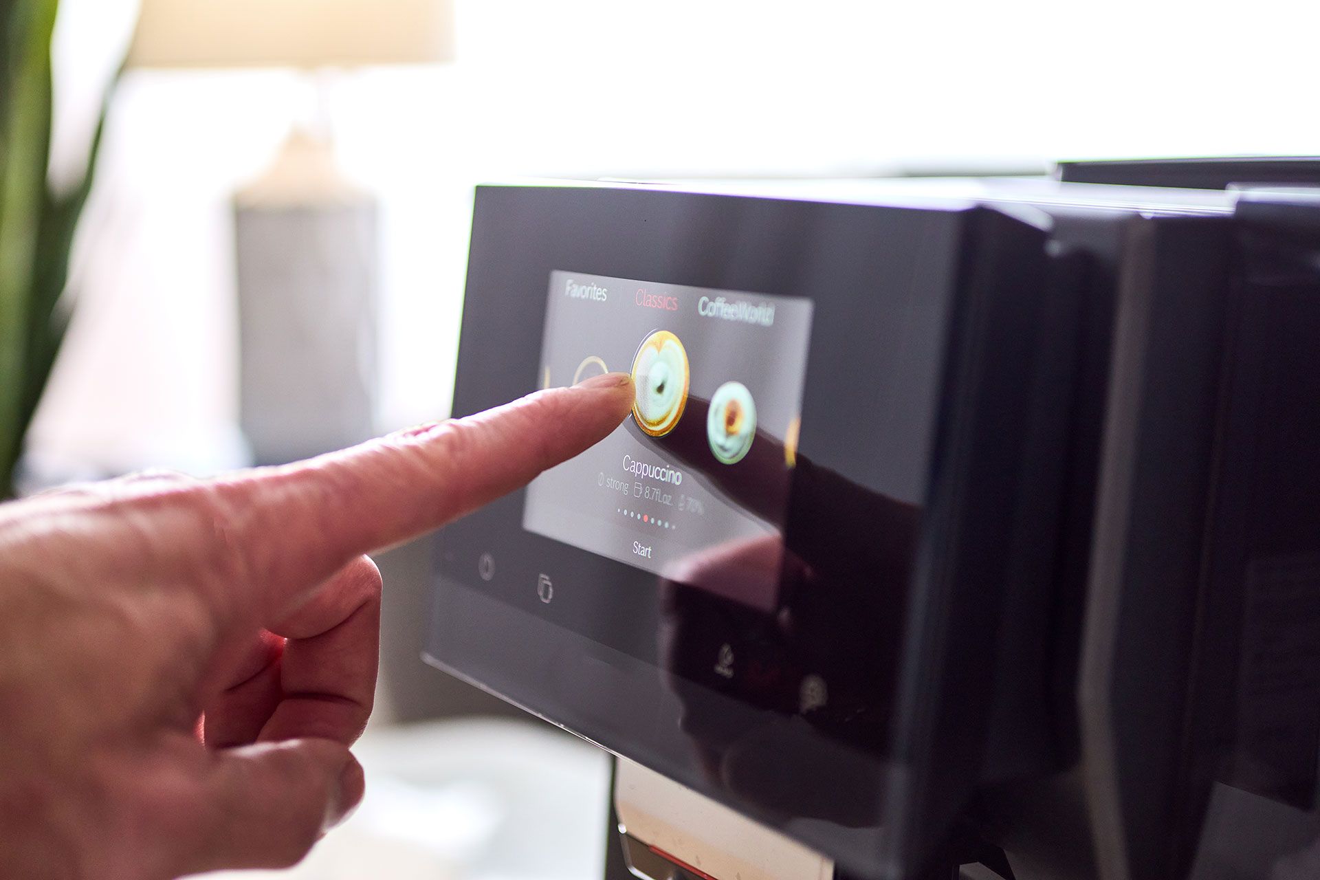 A person is pressing a button on a coffee machine with their finger.
