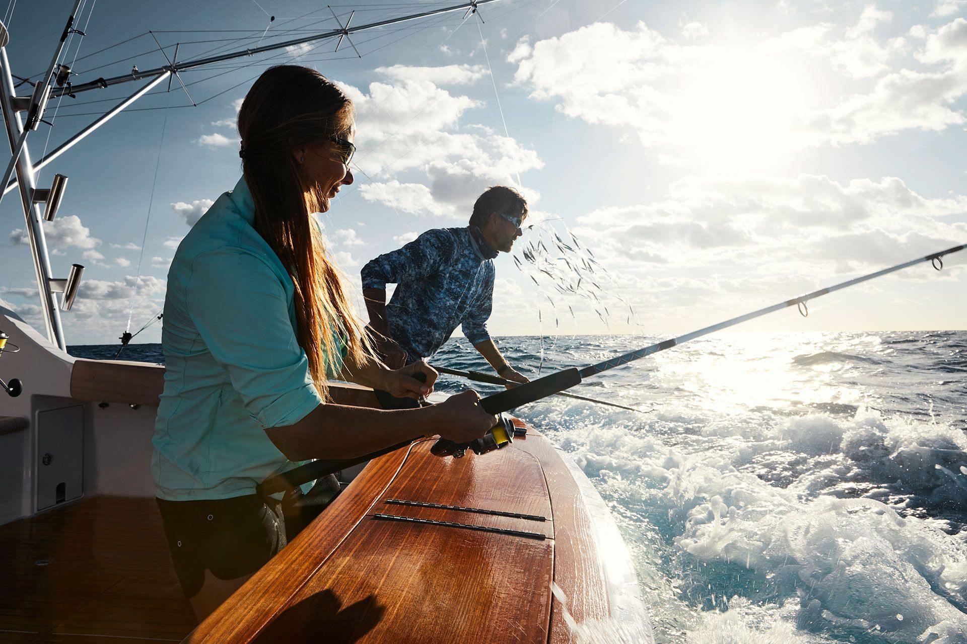 A man and a woman are fishing on a boat in the ocean.