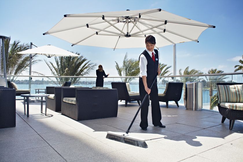 A man is mopping the floor on a balcony with umbrellas
