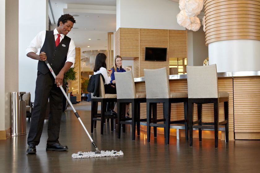 A man is mopping the floor in a restaurant.