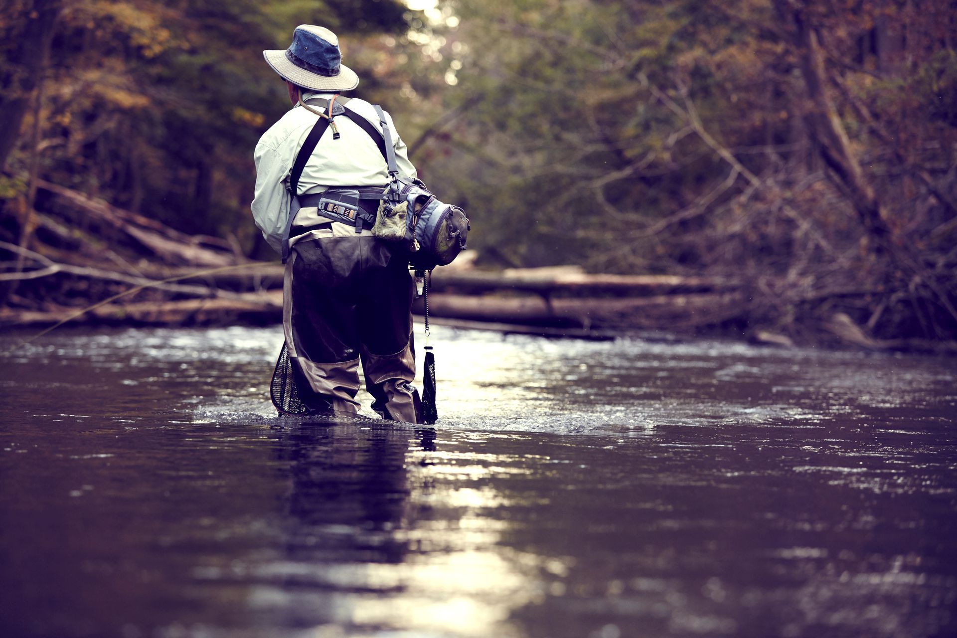 A man in a hat is fishing in a river.