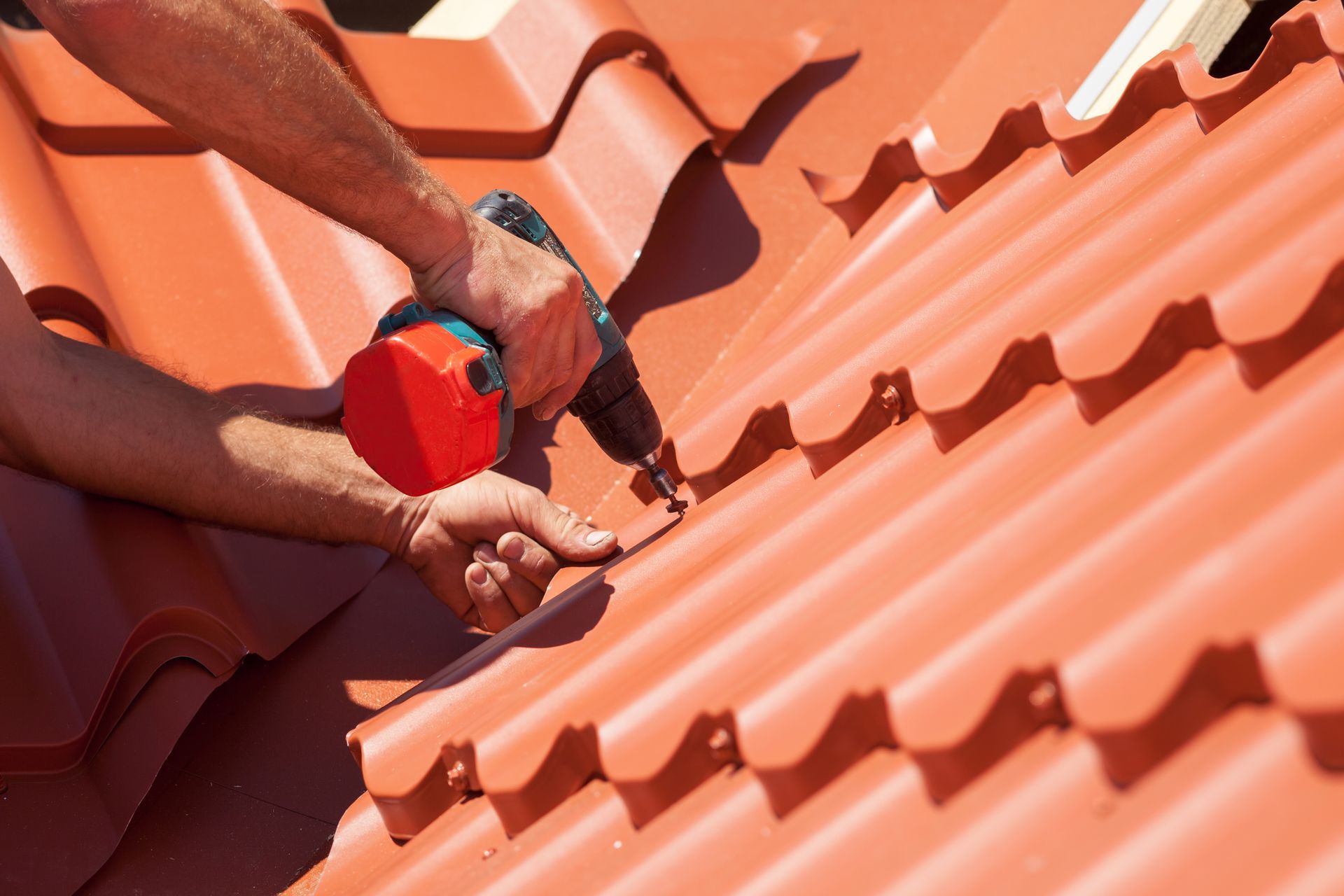 A man is working on a roof with a drill.