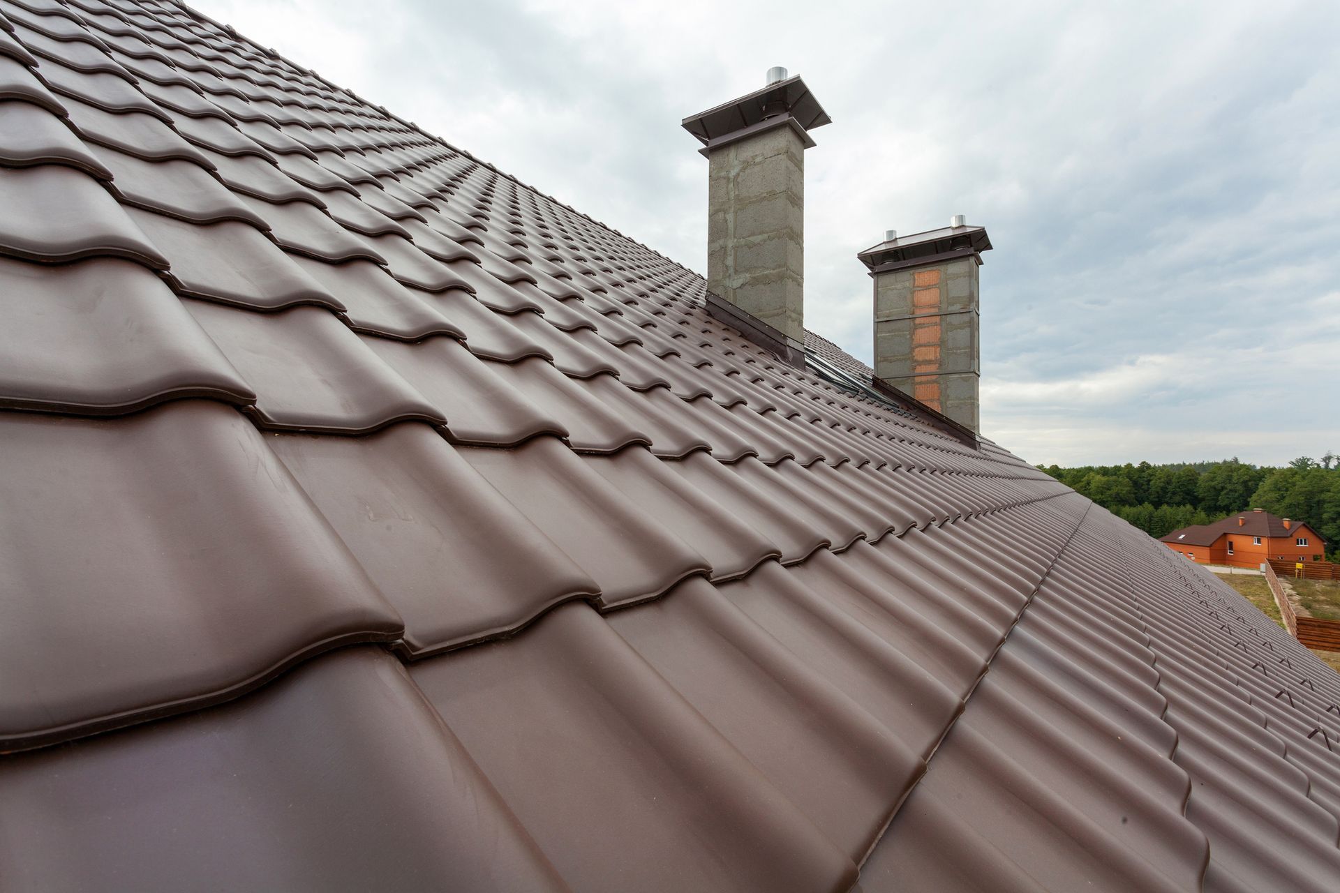 The roof of a house with two chimneys on it.