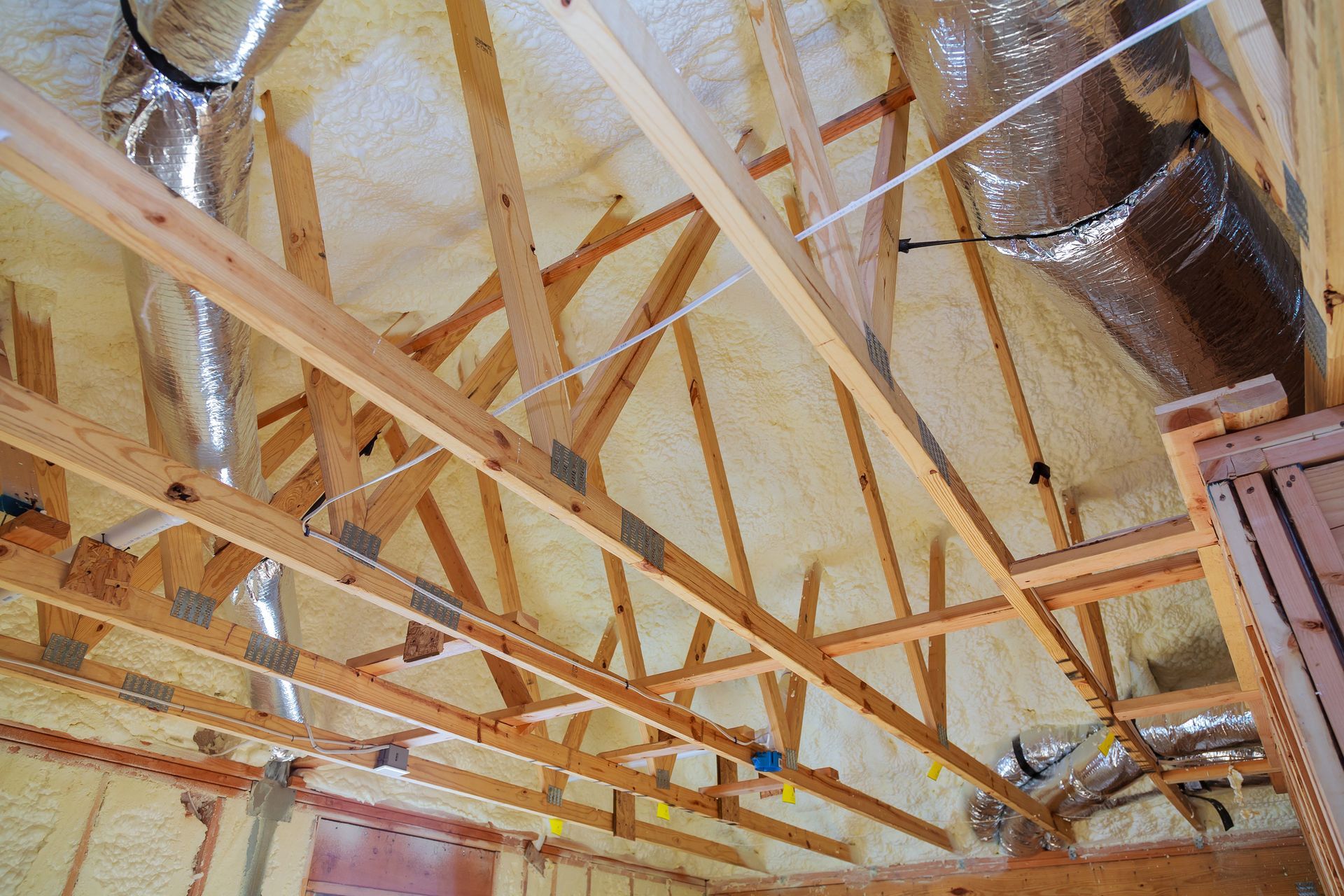 The ceiling of a house is being insulated with spray foam.