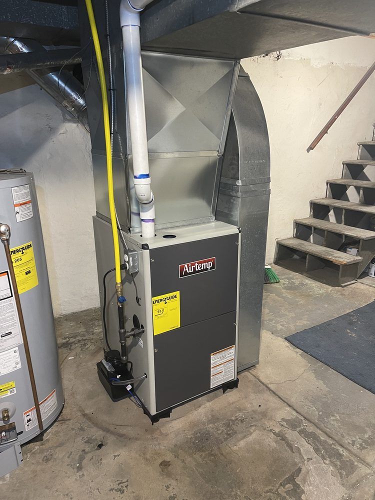 A gas heater is sitting in a basement next to a water heater.