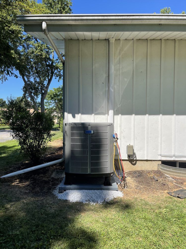 A large air conditioner is sitting on the side of a house.
