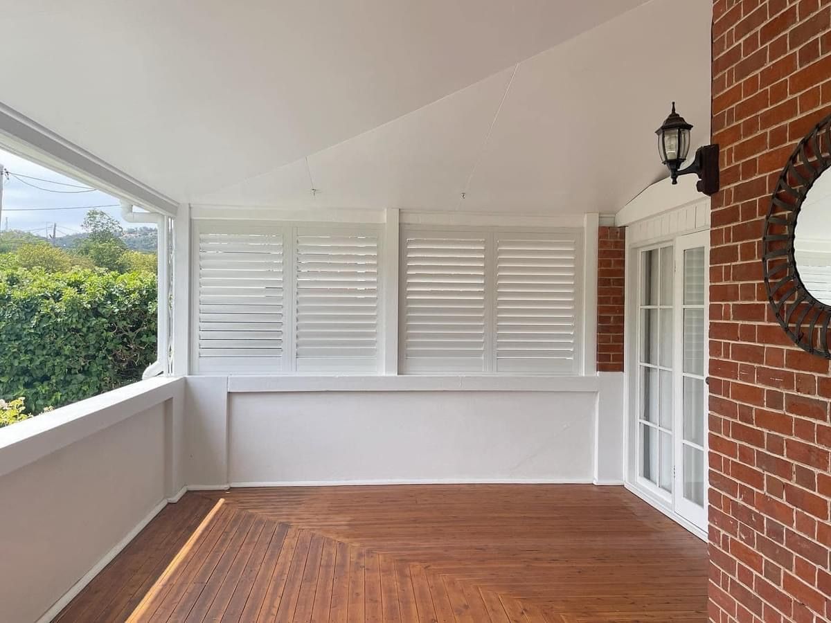An empty porch with shutters and a mirror on the wall.