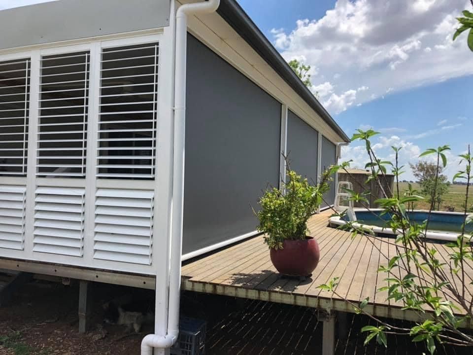 A house with shutters on the windows and a potted plant on the deck.