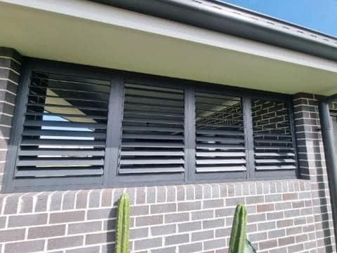 A brick building with a window with shutters on it.