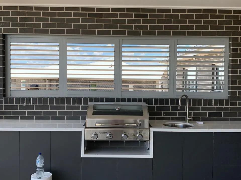A kitchen with a grill and shutters on the windows.