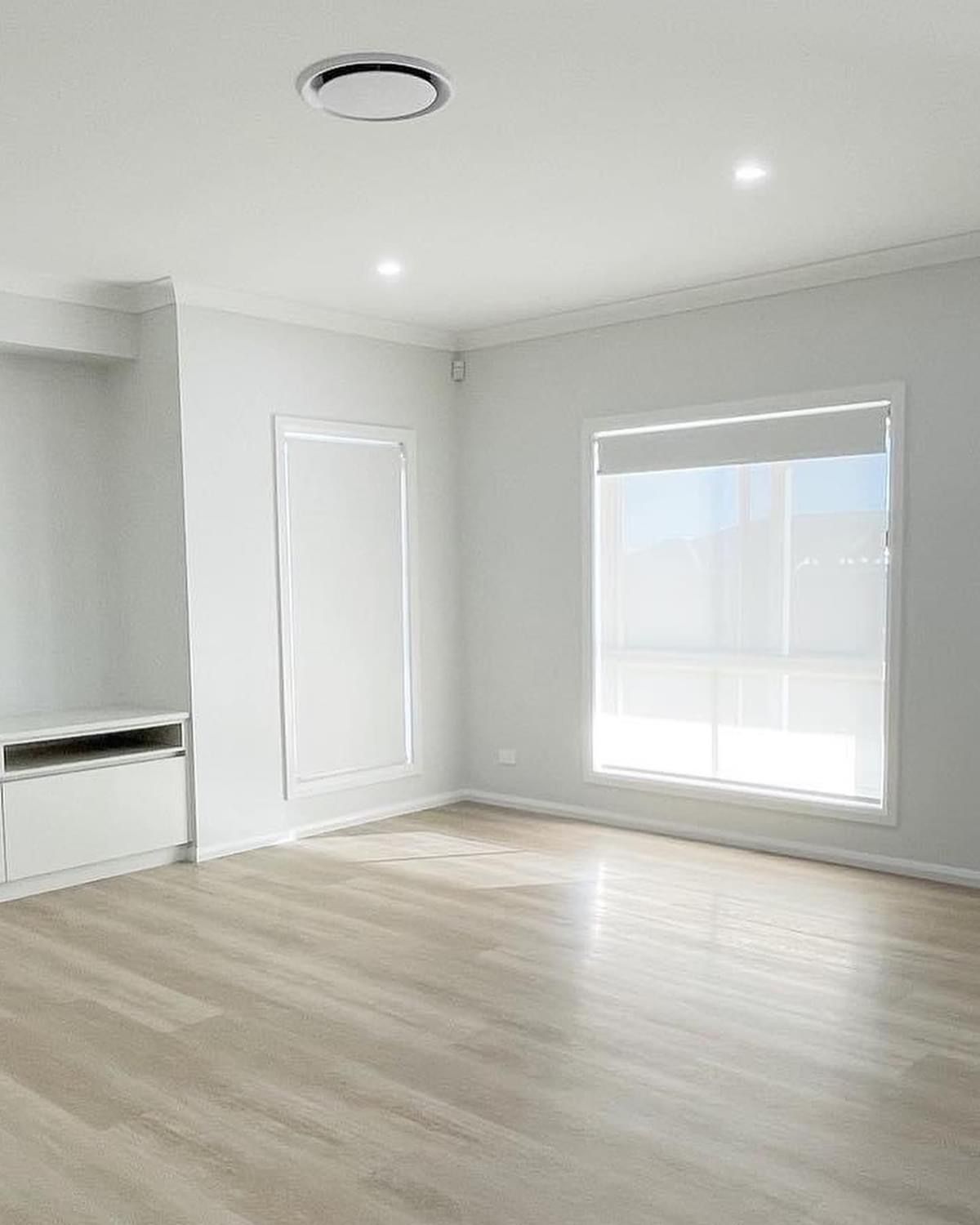 An empty living room with hardwood floors and white walls.