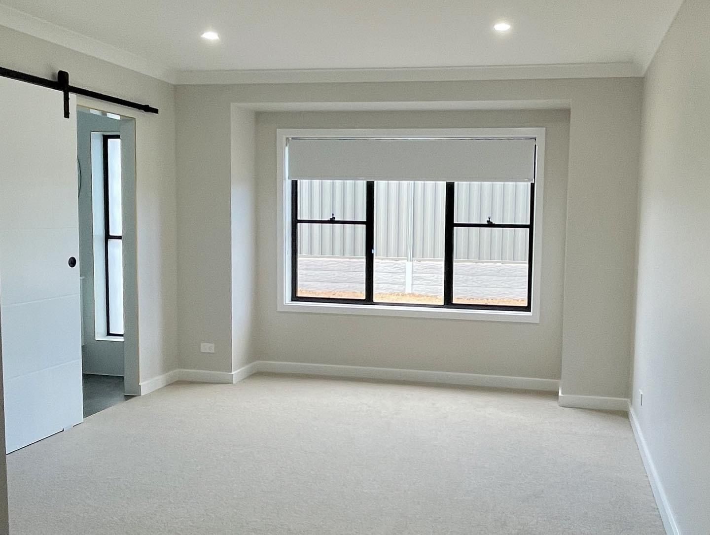 An empty room with a window and a sliding barn door