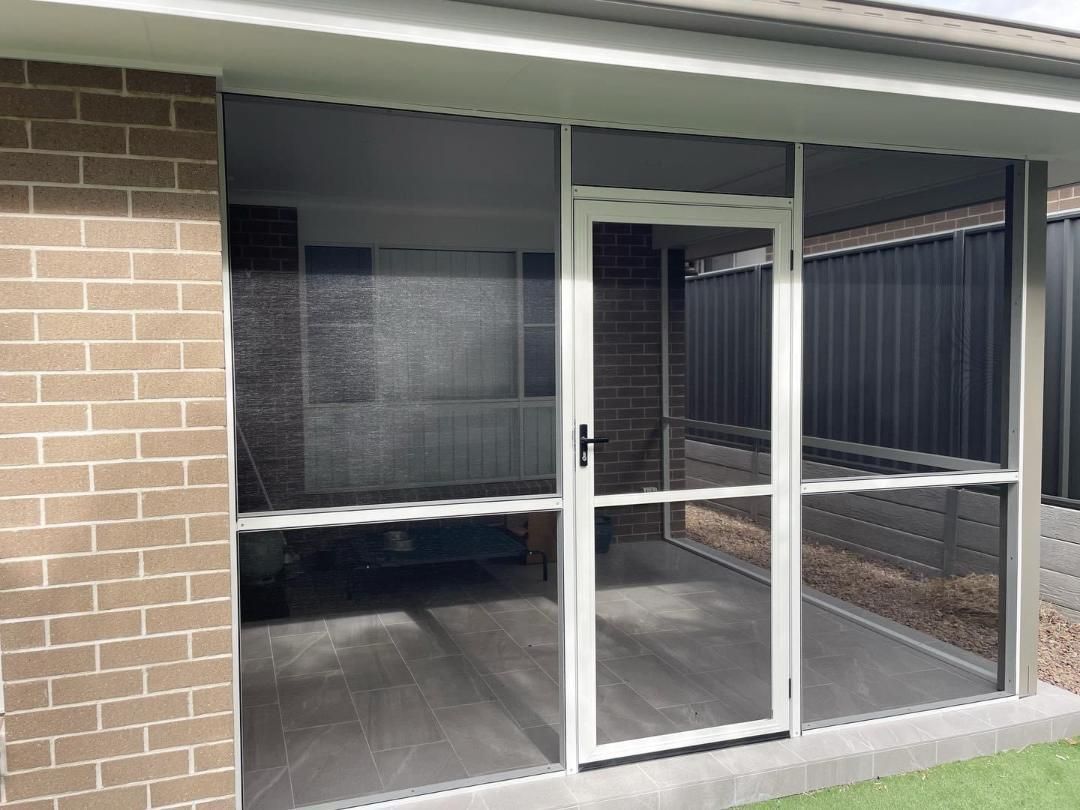 A screened in porch with sliding glass doors and a brick wall.
