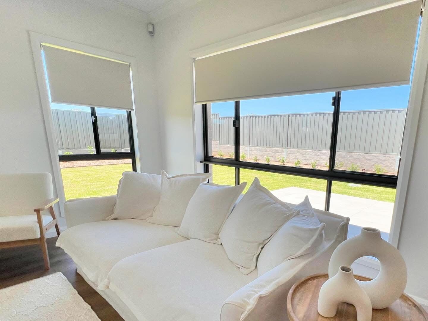 A white wall with a window with black blinds on it