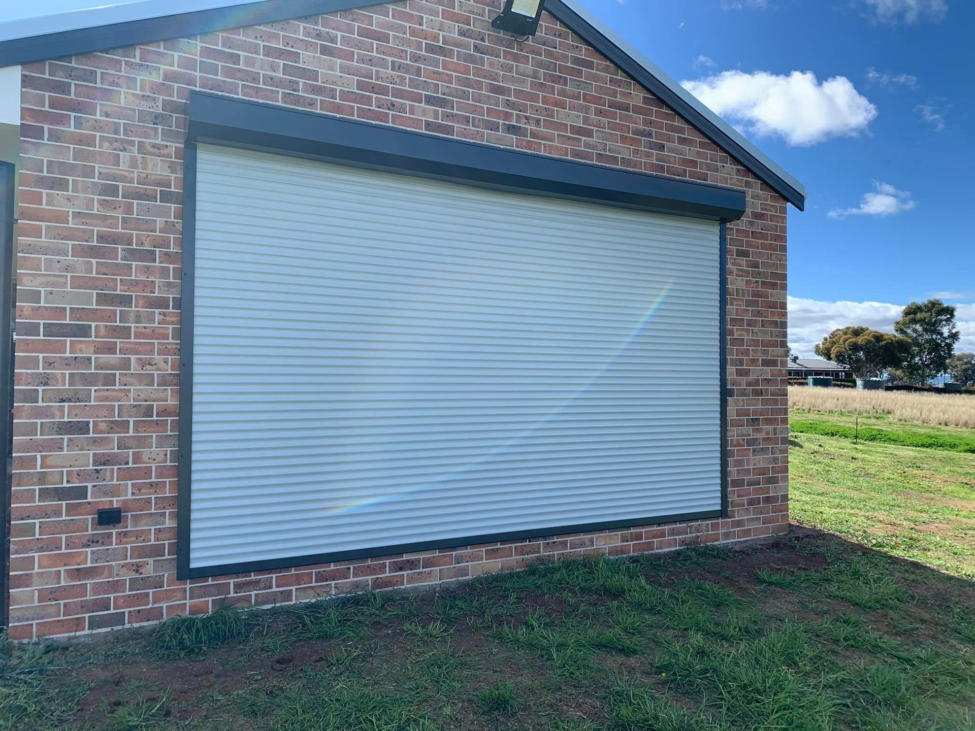 A brick building with a white roller shutter on the side of it.