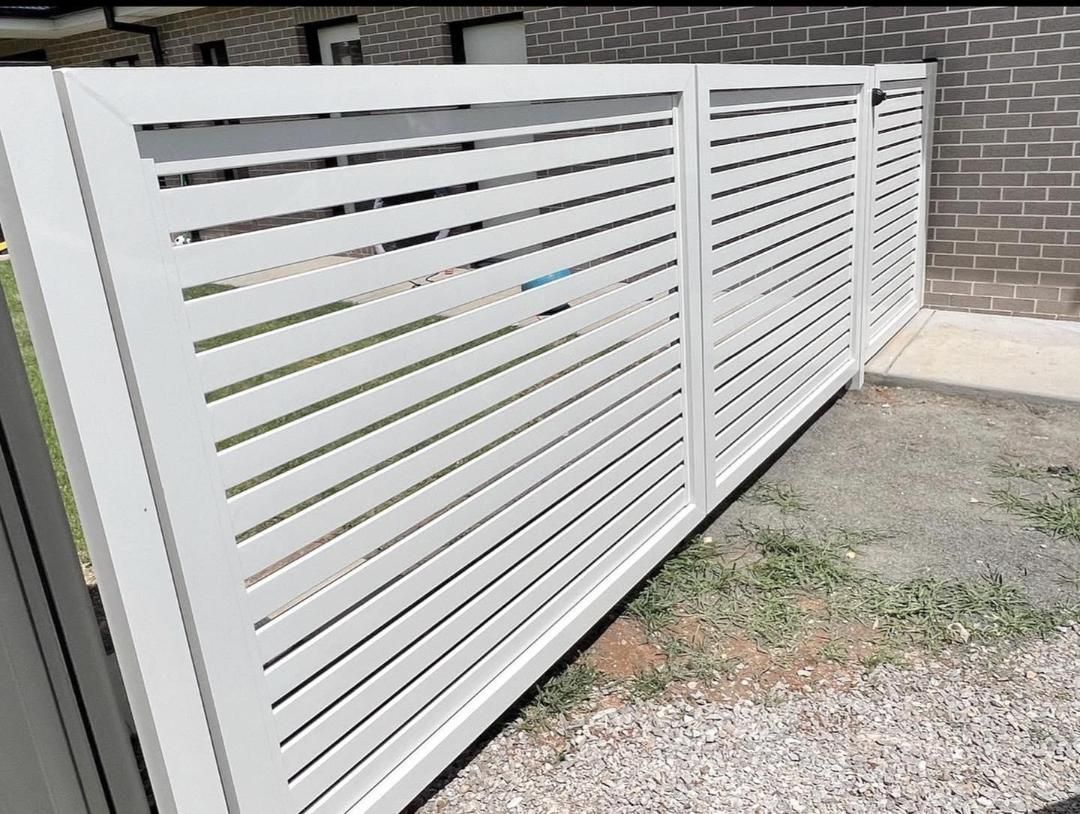 A white fence is sitting in front of a brick building.