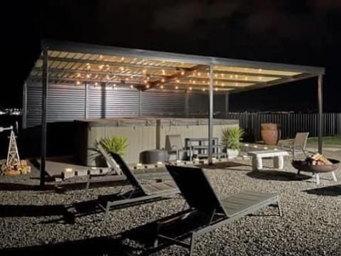 There is a hot tub under a pergola in the backyard at night.