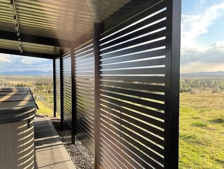 A hot tub is sitting under a pergola with a view of a field.
