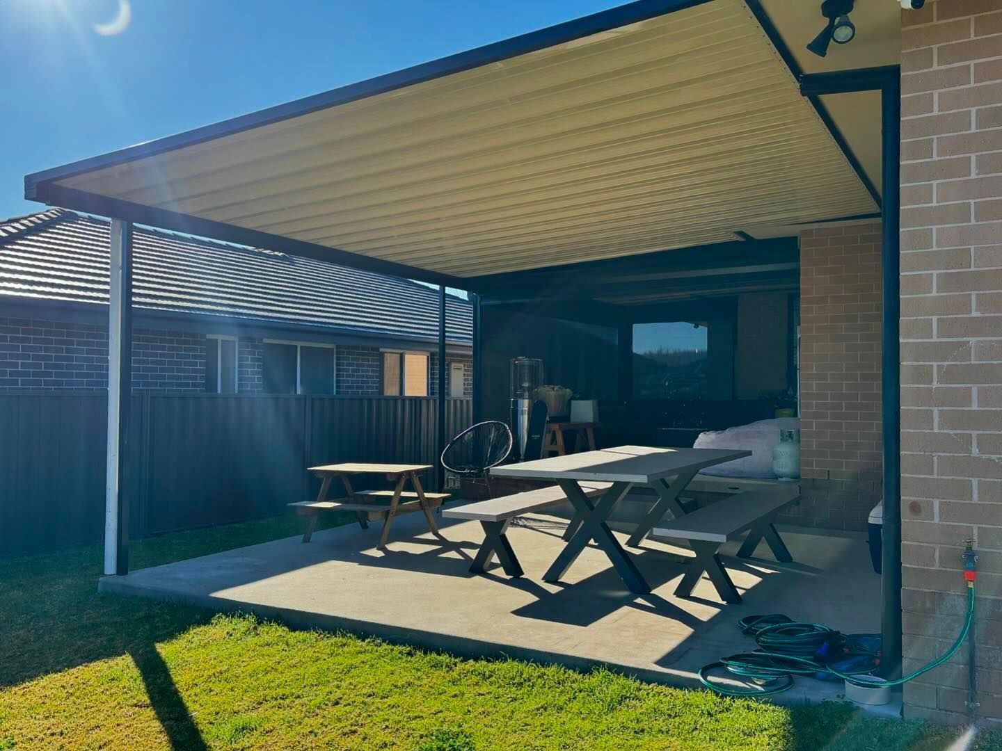 A patio with a picnic table and benches under a canopy.