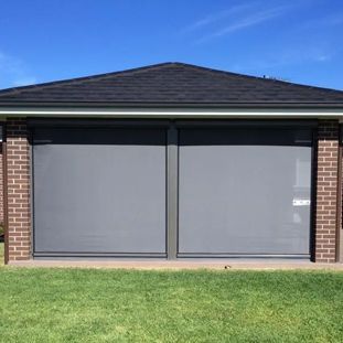 A brick house with a black roof and a gray garage door.