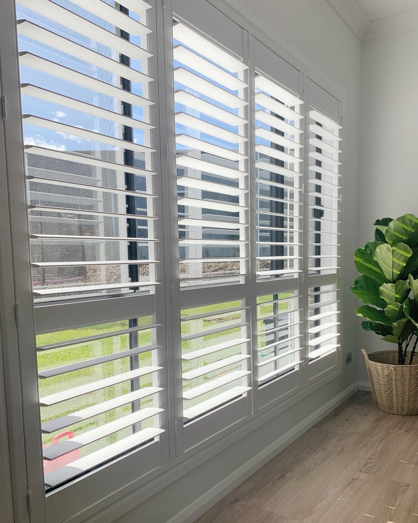 A bedroom with a bed and a window with shutters open.