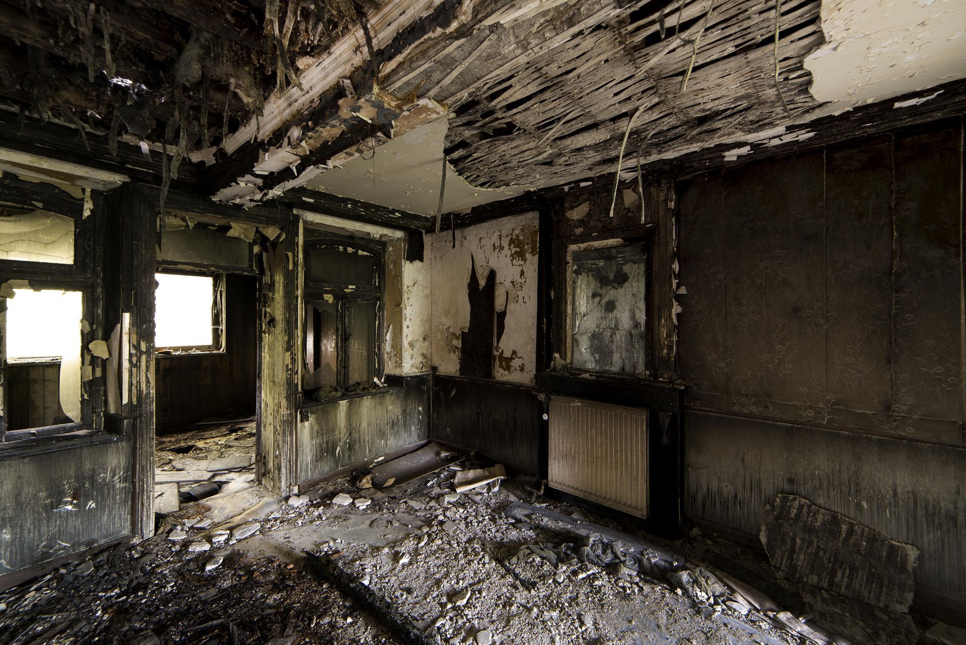 Interior view of a room destroyed by fire, charred walls and debris covering the floor.