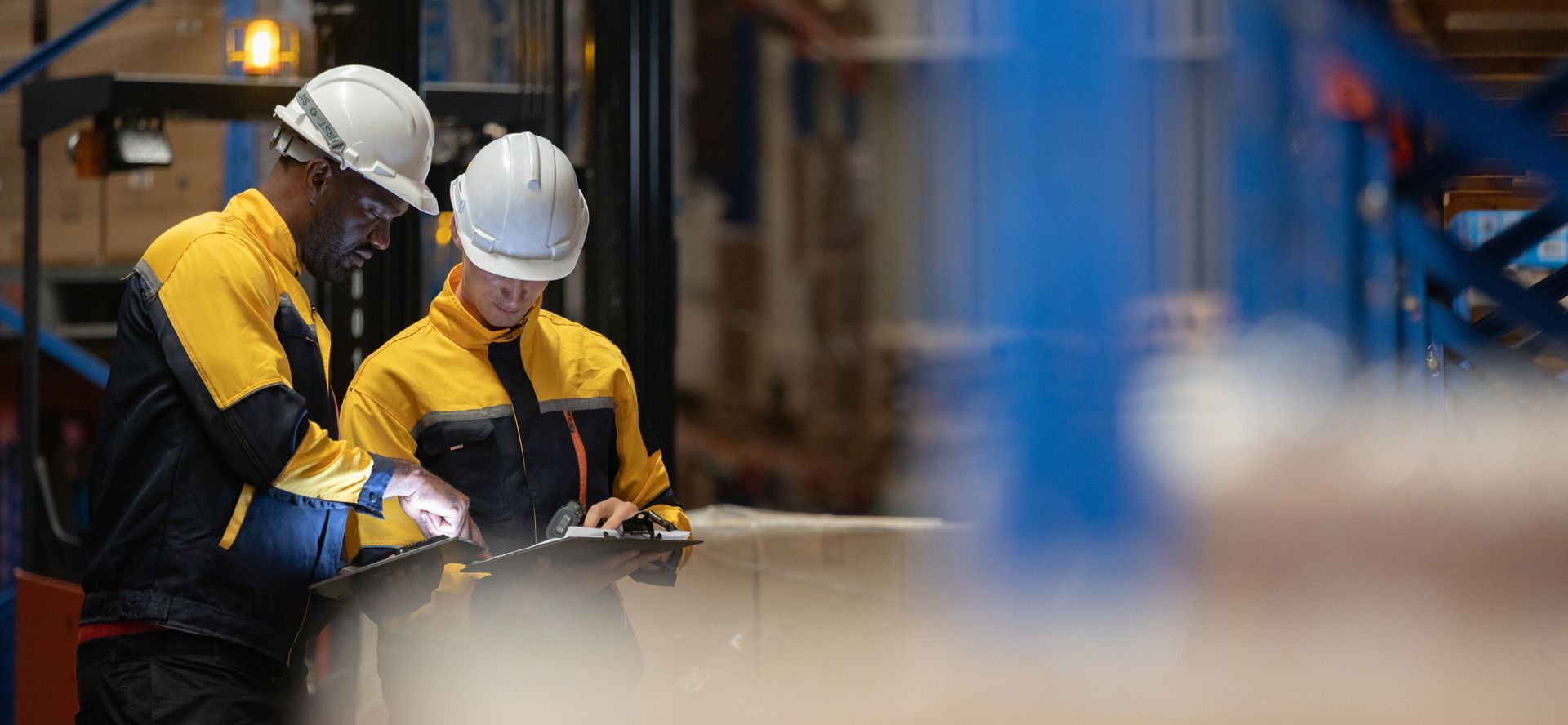 Two warehouse workers wearing safety helmets.