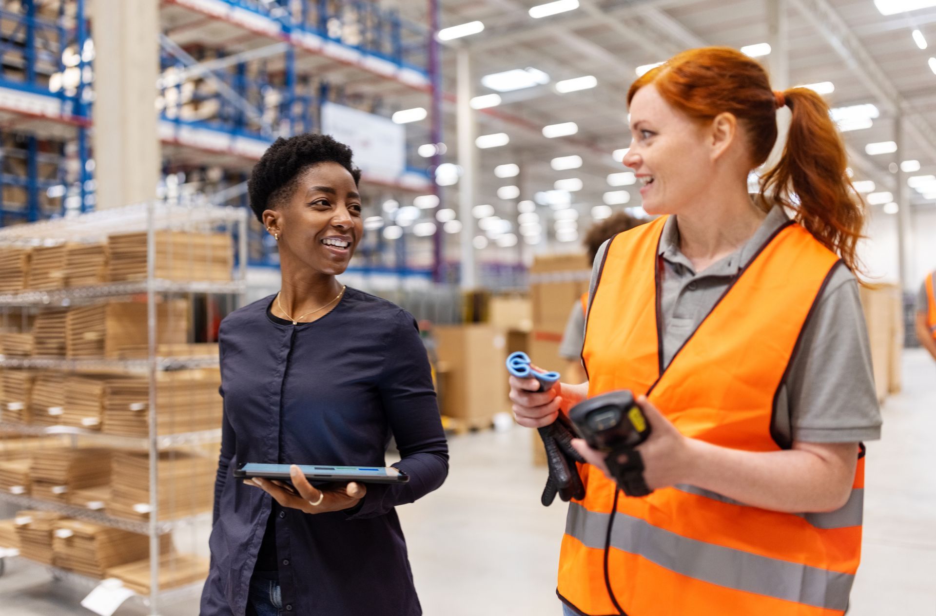 Warehouse workers discussing logistics while walking through a large storage facility.