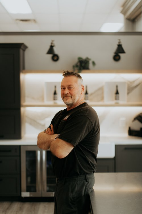 a man standing in a kitchen with his arms crossed