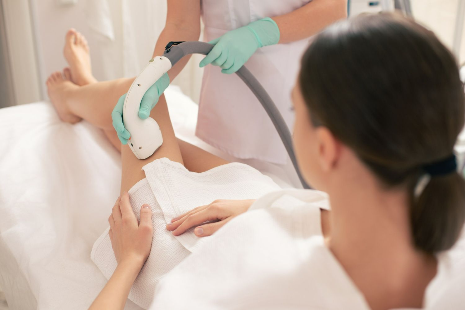 A woman is getting a laser hair removal treatment on her leg.