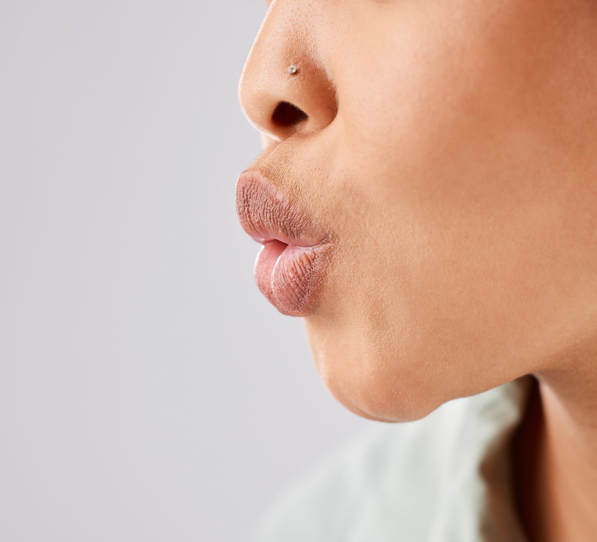 A woman with a nose ring is blowing a kiss.