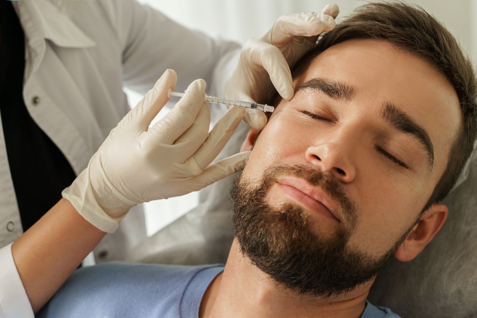 Person receiving an injection near the eye; medical professional in gloves.