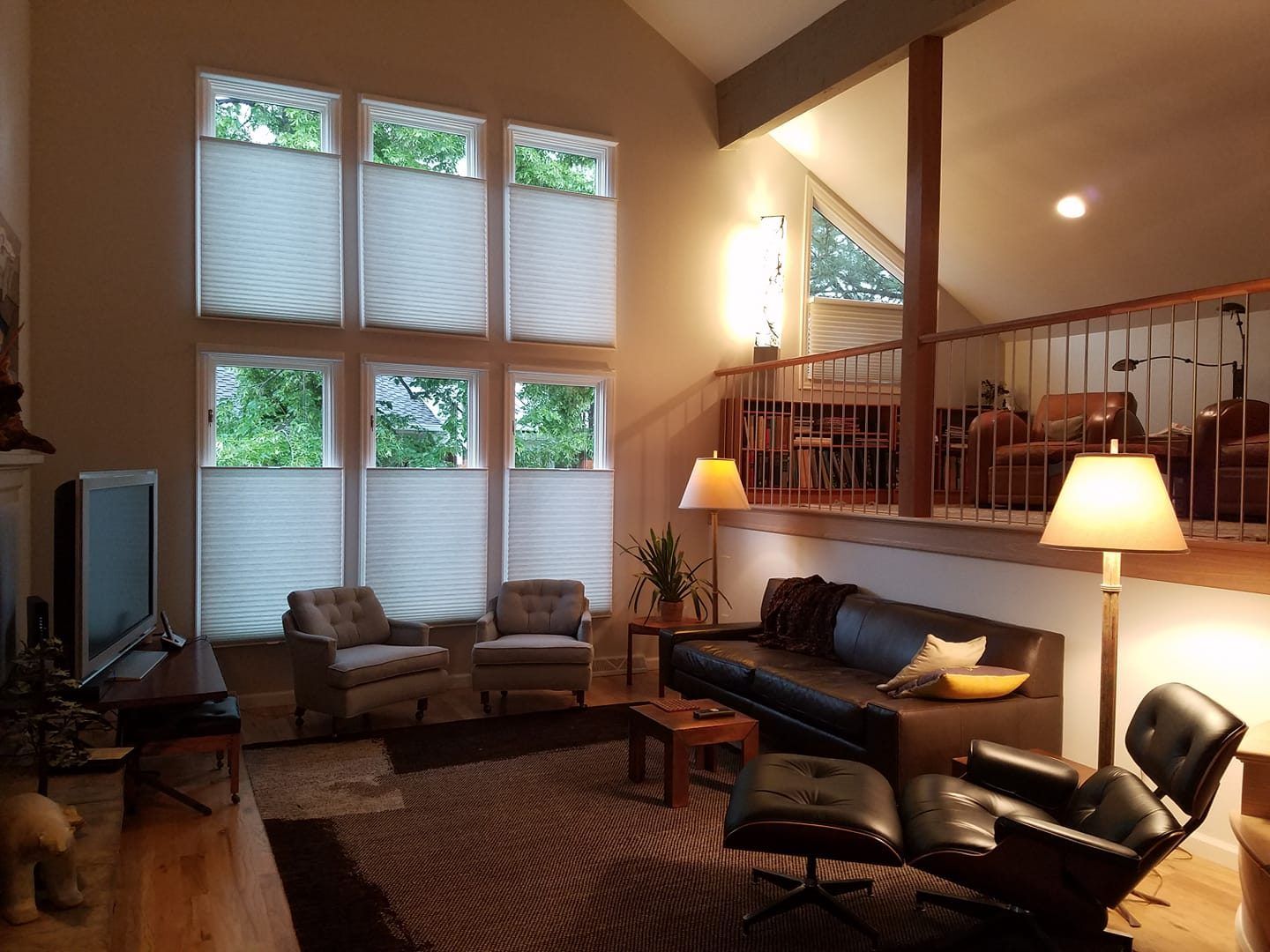 A living room with a vaulted ceiling and lots of windows and blinds