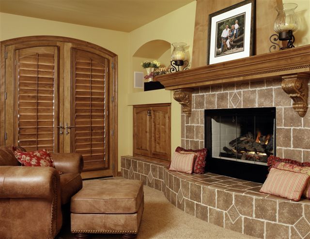 A living room with a fireplace and wooden shutter installed on door.