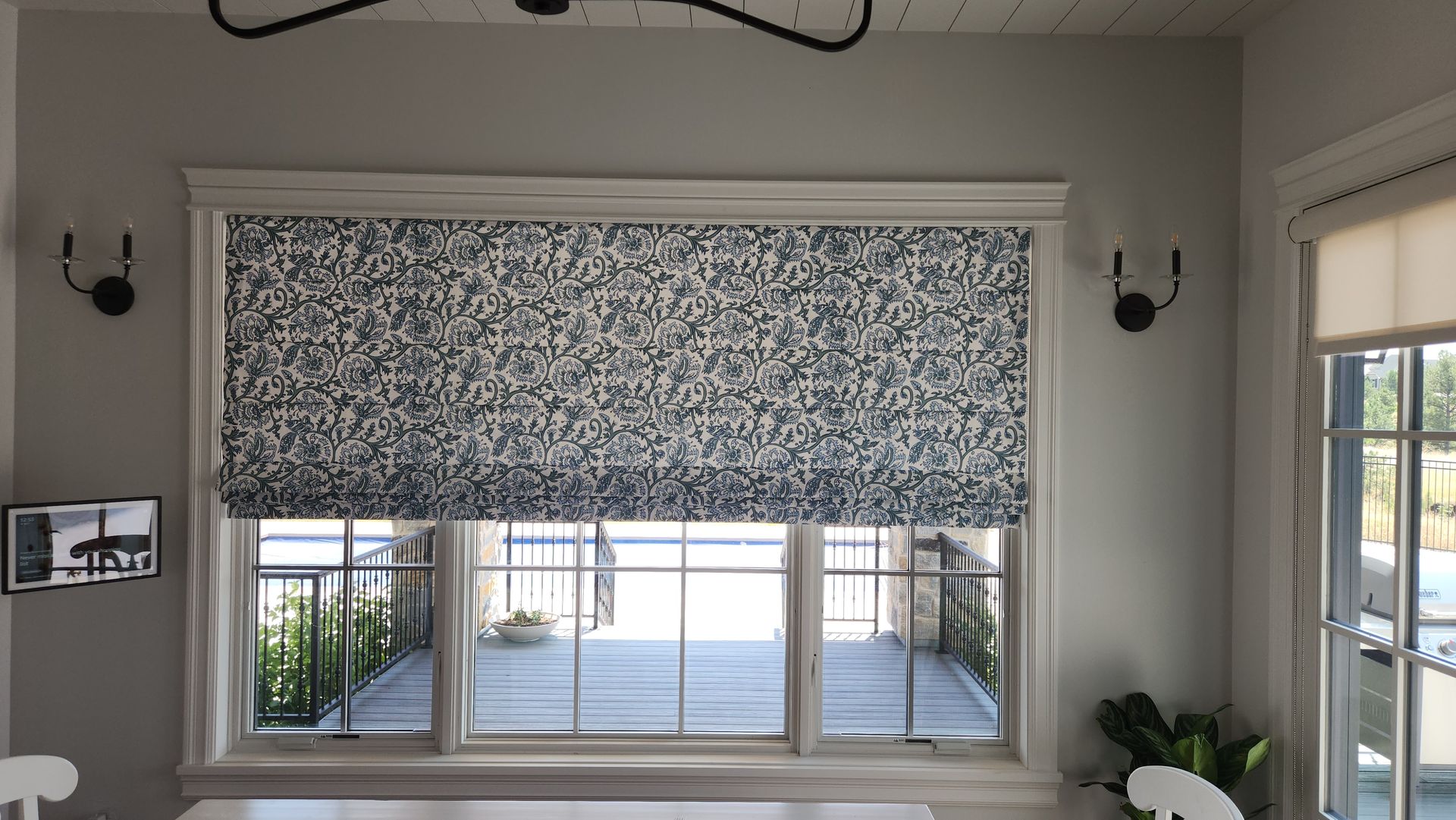 A dining room with a large window with roman shades on it