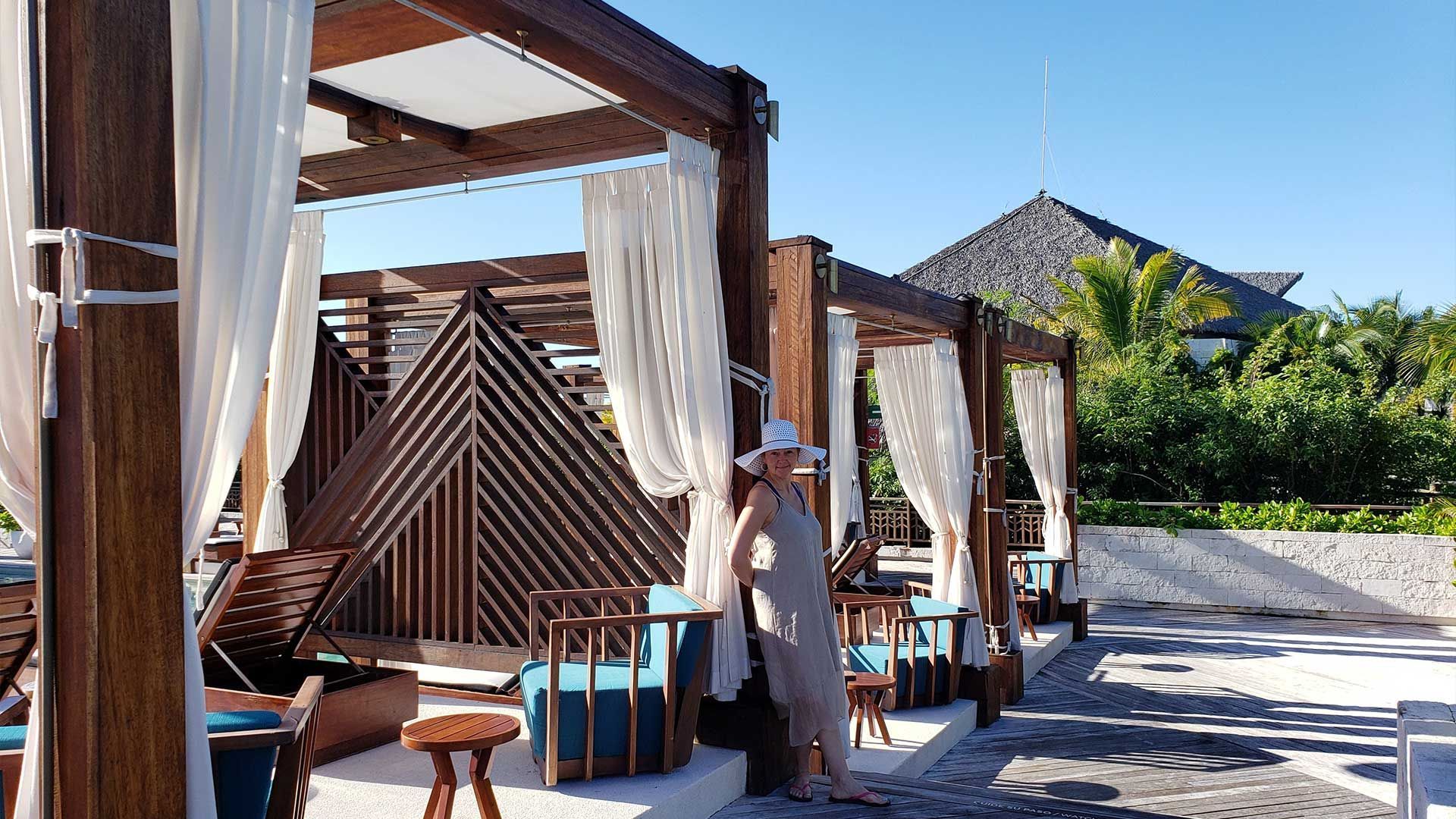 A woman is standing under a canopy on a beach.